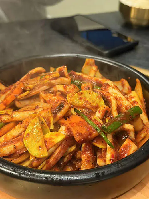 Spicy stir-fried squid with vegetables in a stone bowl at Mr.Kimchi Korean Bistro, a Korean Restaurant in Oklahoma City